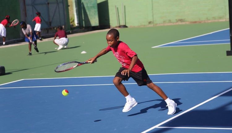 A YOUNG BOY PLAYS TENNIS DURING A SUMMER SPORTS CAMP