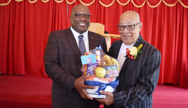 Prime Minister Dr the Hon Timothy Harris (left) presenting a fruit basket to Bishop George C. Gilfillan on his 88th birthday on Sunday August 16.