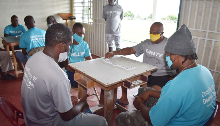 Simeon ‘Cuban’ Liburd of Unity Domino Club, closely watched by Captain Desmond ‘Fergie’ Rawlins (standing), in action when they beat Phillips Domino Club.