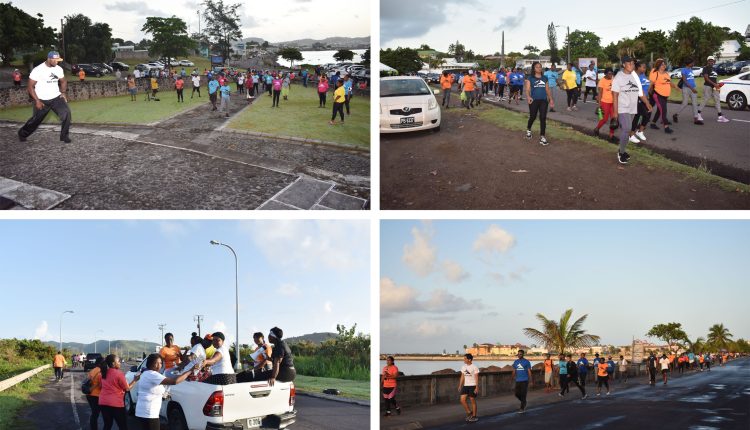 Fitness Guru Wayne Liddie leading participants in warm-up exercises; participants setting off; walking along New Town Bay Road; distribution of water.