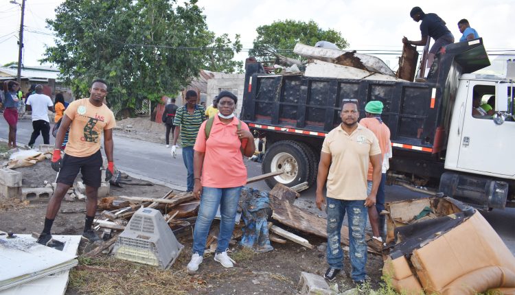 Mr Delwayne Delaney (in shorts) helping remove household waste;