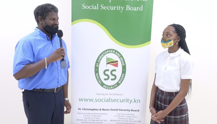 (l-r) Mr. Donovan Herbert, Senior Branch Manager of the St. Christopher and Nevis Social Security Board, Nevis Branch thanking Ms. Zwena Jones of Zee’s Exquisite Apparel Line (ZEAL), a budding entrepreneur, recipient of a St. Christopher and Nevis Social Security Board Scholarship and a student of the Nevis Sixth Form College at the Social Security’s Board Room at Pinney’s Estate on September 25, 2020, for her donation of 25 fabric masks to the Branch members to assist in their fight against COVID-19