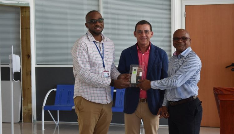Mr. De Silva (center) presents a thermometer to Minister Grant (right) and Chairman Hobson (left)