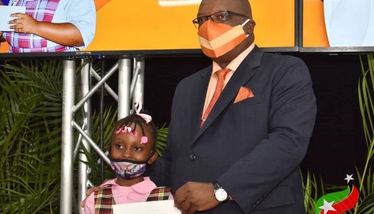 Prime Minister Dr. the Hon. Timothy Harris presents cheque to Cayon Primary School student Breanna Berry during the Help-a-Child programme
