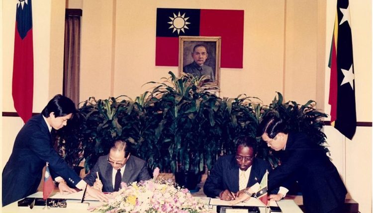 Shows Dr. Kennedy Simmonds (seated right) signing documents to officially establish diplomatic ties with the Republic of China (Taiwan)