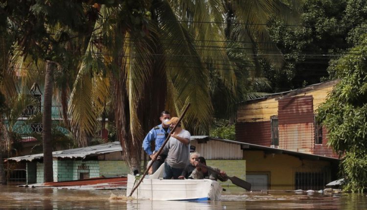 Residents paddle a boat through a flooded street in the aftermath of Hurricane Eta in Planeta, Honduras, Thursday, Nov. 5, 2020. The storm that hit Nicaragua as a Category 4 hurricane on Tuesday had become more of a vast tropical rainstorm, but it was advancing so slowly and dumping so much rain that much of Central America remained on high alert. (AP Photo/Delmer Martinez)