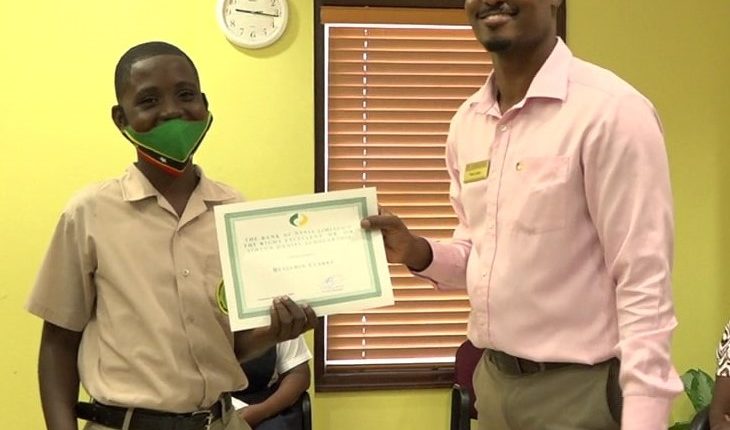 Mr. Benjamin Clarke of the Gingerland Secondary School receiving the Bank of Nevis Limited’s Right Excellent Dr. Sir Simeon Daniel Scholarships for 2020 presented by Pheon Jones, Marketing Officer and Member of the Scholarship Committee on December 04, 2020