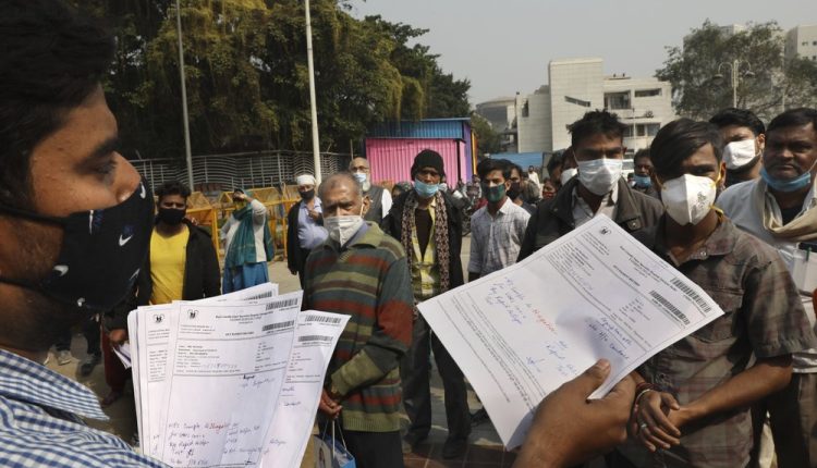 A health worker hands out COVID-19 test results in New Delhi, India, Thursday, Feb. 11, 2021. When the coronavirus pandemic took hold in India, there were fears it would sink the fragile health system of the world’s second-most populous country. Infections climbed dramatically for months and at one point India looked like it might overtake the United States as the country with the highest case toll. But infections began to plummet in September, and experts aren’t sure why. (AP Photo/Manish Swarup)