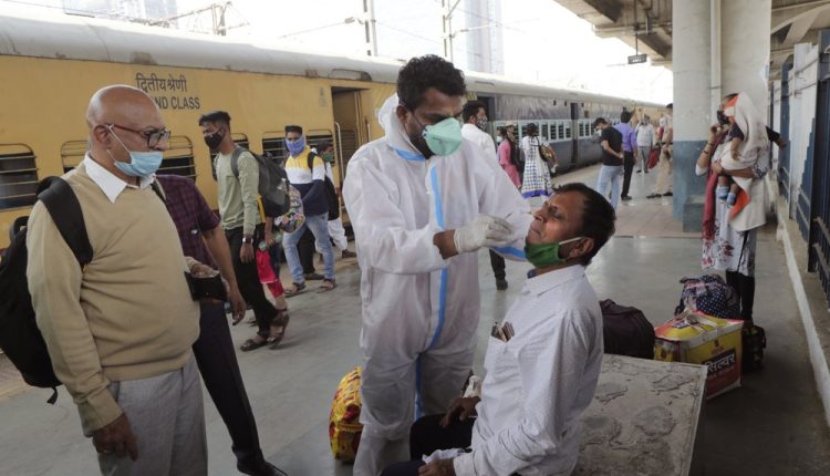 A health worker takes a swab sample of a commuter to test for COVID-19 at a train station in Mumbai, India