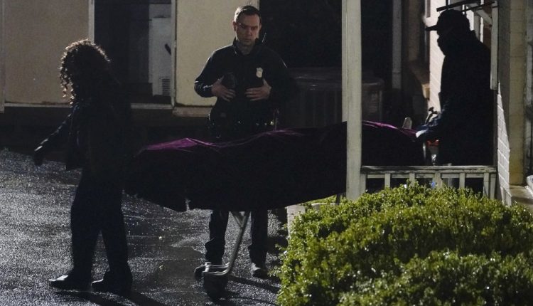 A police officer watches as a body is taken from the Gold Spa massage parlor after a shooting, late Tuesday, March 16, 2021, in Atlanta. Shootings at two massage parlors in Atlanta and one in the suburbs left multiple people dead, many of them women of Asian descent, authorities said. A 21-year-old man suspected in the shootings was taken into custody in southwest Georgia hours later after a manhunt, police said. (AP Photo/Brynn Anderson)