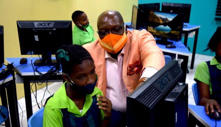 A student of the Violet Petty Primary School demonstrating her competence in the use of ICT to Prime Minister Harris