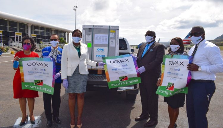 Local officials, including Prime Minister Dr. the Hon. Timothy Harris (3rd from right) and Minister of Health, the Hon. Akilah Byron-Nisbett (3rd from left), accept the COVID-19 vaccines upon arrival at the RLB International Airport