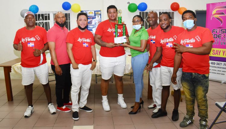 Marketing and Product Development Officer Ms Chantelle Rochester, presenting the Development Bank of St. Kitts and Nevis/St. Kitts National Domino Association trophy to Los Fuertes del Domino.