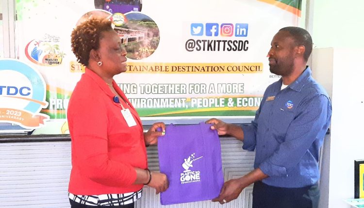 Chairperson of the St. Kitts Sustainable Destination Council, Diannille Taylor-Williams presenting reusable bags to Marketing Assistant at TDC, Dominic Matthew